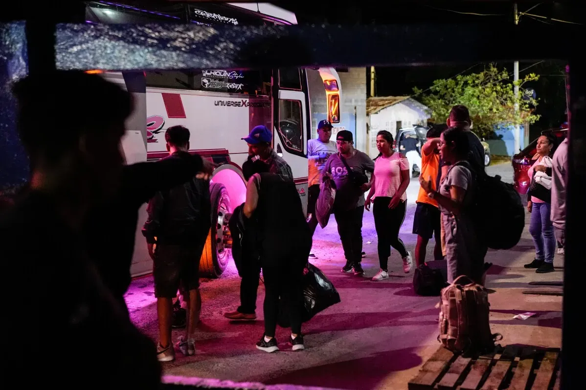 مجموعة من المهاجرين في بنما يستعدون للصعود إلى حافلة، مع وجود حقائبهم، وسط أجواء غير واضحة بسبب القيود المفروضة عليهم.