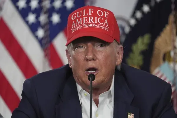 ترامب يرتدي قبعة حمراء مكتوب عليها "GULF OF AMERICA" خلال مؤتمر صحفي، مع العلم الأمريكي خلفه، في سياق حديثه عن قضايا حرية التعبير.