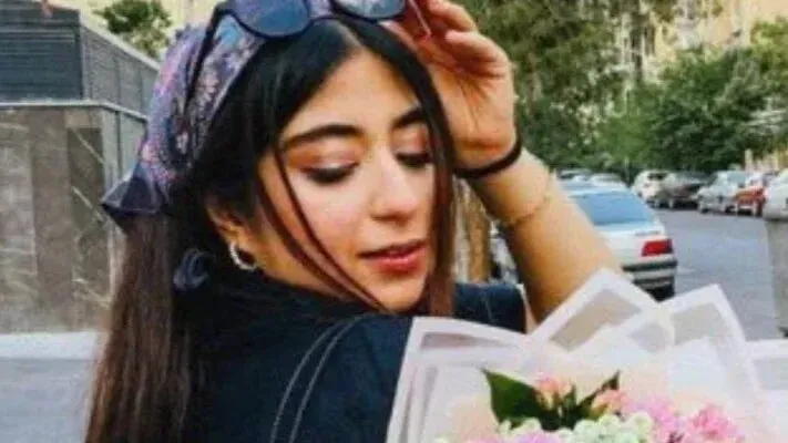 صورة لبارنيا عباسي، شاعرة شابة تحمل باقة من الزهور، تعكس روحها الحية وأحلامها المفقودة بعد الغارة الإسرائيلية.
