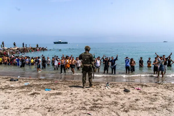 جندي إسباني يواجه مجموعة كبيرة من المهاجرين يعبرون شاطئ سبتة، في ظل أزمة الهجرة وتأثيرها على استضافة كأس العالم 2030.