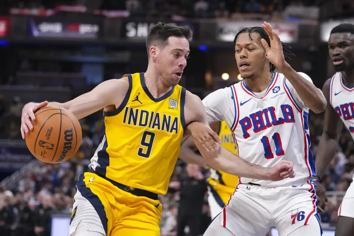 لاعب من فريق إنديانا بيسرز يحمل الكرة ويحاول المراوغة أمام مدافع من فريق فيلادلفيا 76ers خلال مباراة كرة سلة مثيرة.