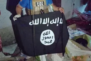 شخص يحمل علمًا أسود يحمل شعار تنظيم داعش، في موقع اشتباك مع القوات الفلبينية في جنوب البلاد، حيث قُتل عشرة مسلحين.