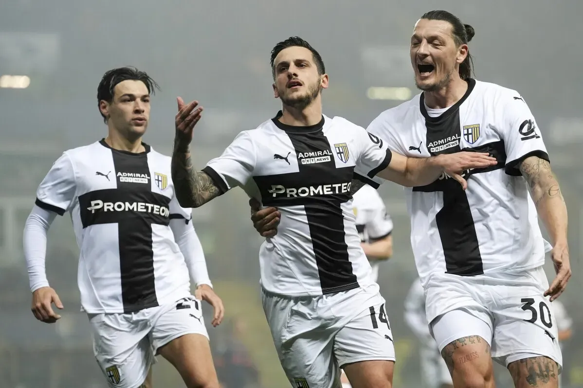 احتفالات فريق بارما بعد تسجيل هدف، مع لاعب يرتدي زي الفريق الأبيض والأسود وسط لاعبَين آخرَين في الخلفية، خلال مباراة في الدوري الإيطالي.