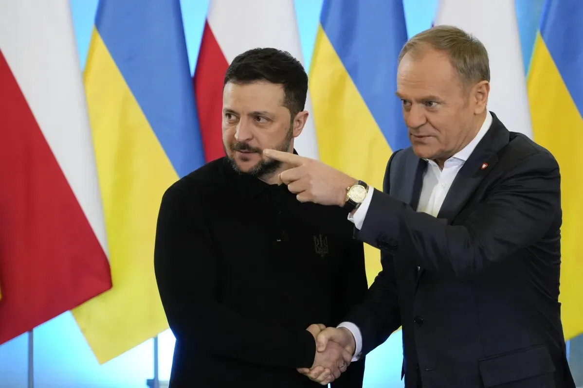اجتماع بين الرئيس الأوكراني فولوديمير زيلينسكي ورئيس الوزراء البولندي دونالد توسك، وسط أعلام بولندا وأوكرانيا، يعكس التعاون الأمني.