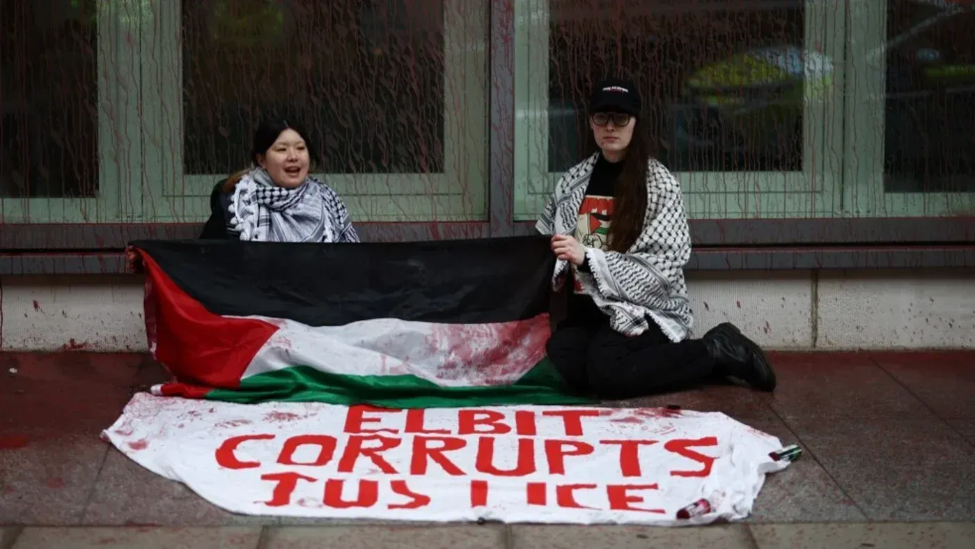 نشطاء يحملون علم فلسطين ولافتة مكتوب عليها "إلبيت تفسد العدالة" خلال احتجاج ضد شركة إلبيت سيستمز في لندن.