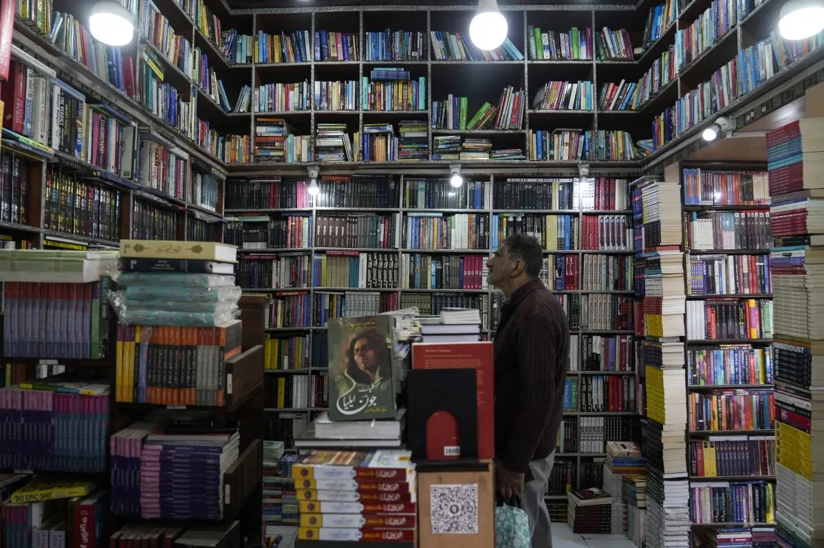 رجل يقف في مكتبة مليئة بالكتب، حيث تمت مصادرة مئات الكتب المرتبطة بمنظمة إسلامية في كشمير، وسط تصاعد الرقابة.
