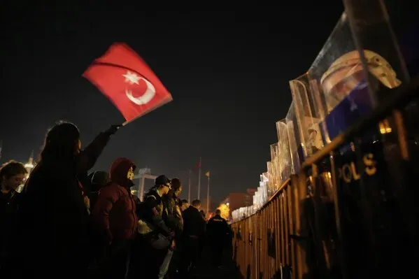 محتجون يحملون علم تركيا أمام صفوف من قوات الشرطة، خلال اشتباكات في إسطنبول تعبيرًا عن رفضهم للاعتقالات السياسية.