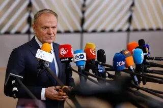 رئيس الوزراء دونالد توسك يتحدث أمام مجموعة من الميكروفونات في البرلمان البولندي، وسط أجواء مشحونة حول اتهامات تمويل مشبوه لشركة Zondacrypto.