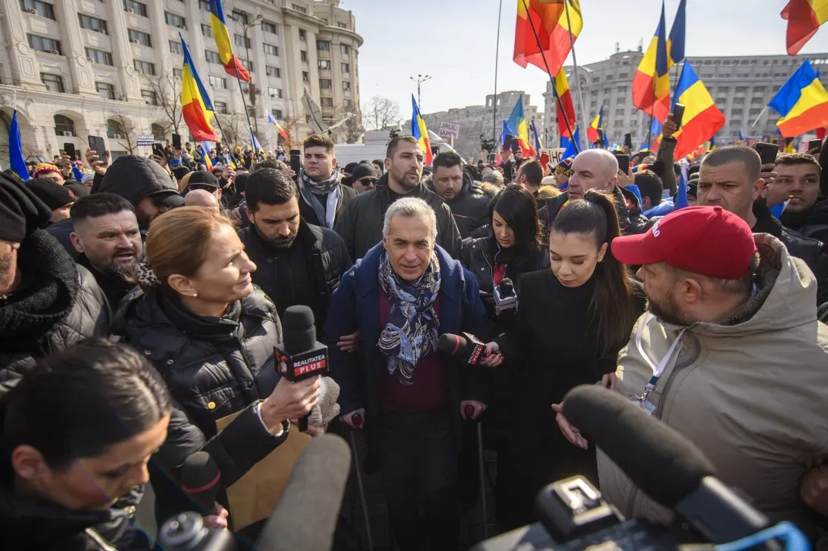 كالين جورجيسكو وسط حشد من مؤيديه خلال مظاهرة في بوخارست، مع أعلام رومانية ترفرف حوله، بينما يتحدث مع وسائل الإعلام.