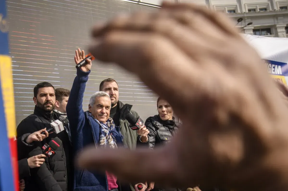 كالين جورجيسكو، المرشح الرئاسي السابق، يلوح بيده وسط حشد من المؤيدين في بوخارست، بعد استجوابه من قبل الشرطة.