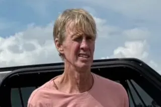 رجل يرتدي قميصًا ورديًا، يبدو متوترًا، يقف بالقرب من سيارة، في سياق محاكمته بتهمة محاولة اغتيال الرئيس ترامب.