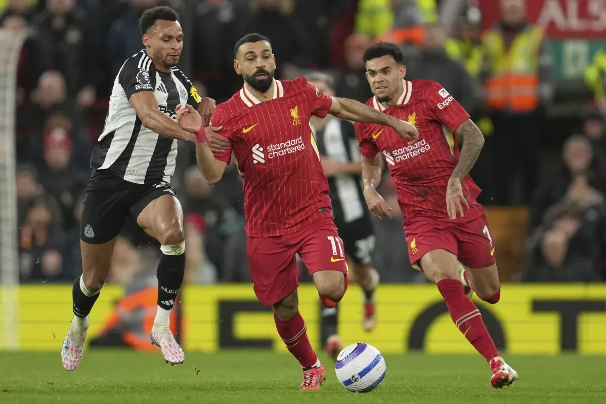 محمد صلاح يتقدم بالكرة وسط لاعبي نيوكاسل، بينما يظهر زملاؤه في فريق ليفربول في الخلف، في مباراة مثيرة ضمن الدوري الإنجليزي.