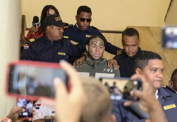 مغني الراب تيكاشي 6IX9ine محاط بأفراد الأمن أثناء مغادرته المحكمة بعد اعترافه بانتهاك شروط الإفراج تحت المراقبة.