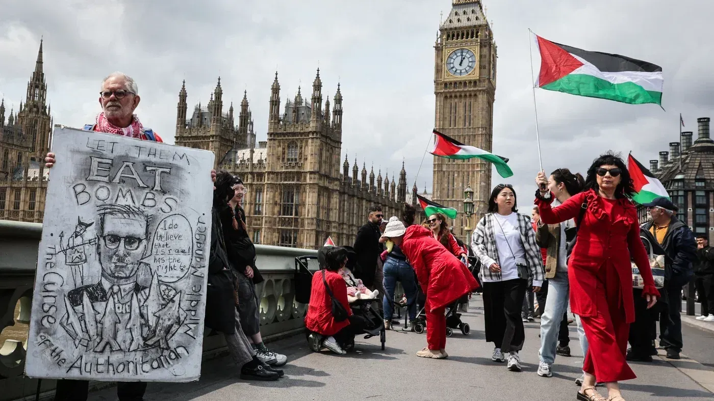 متظاهرون يحملون لافتات وأعلام فلسطينية أمام مبنى البرلمان البريطاني، مع تعبيرات عن دعم حقوق الفلسطينيين.