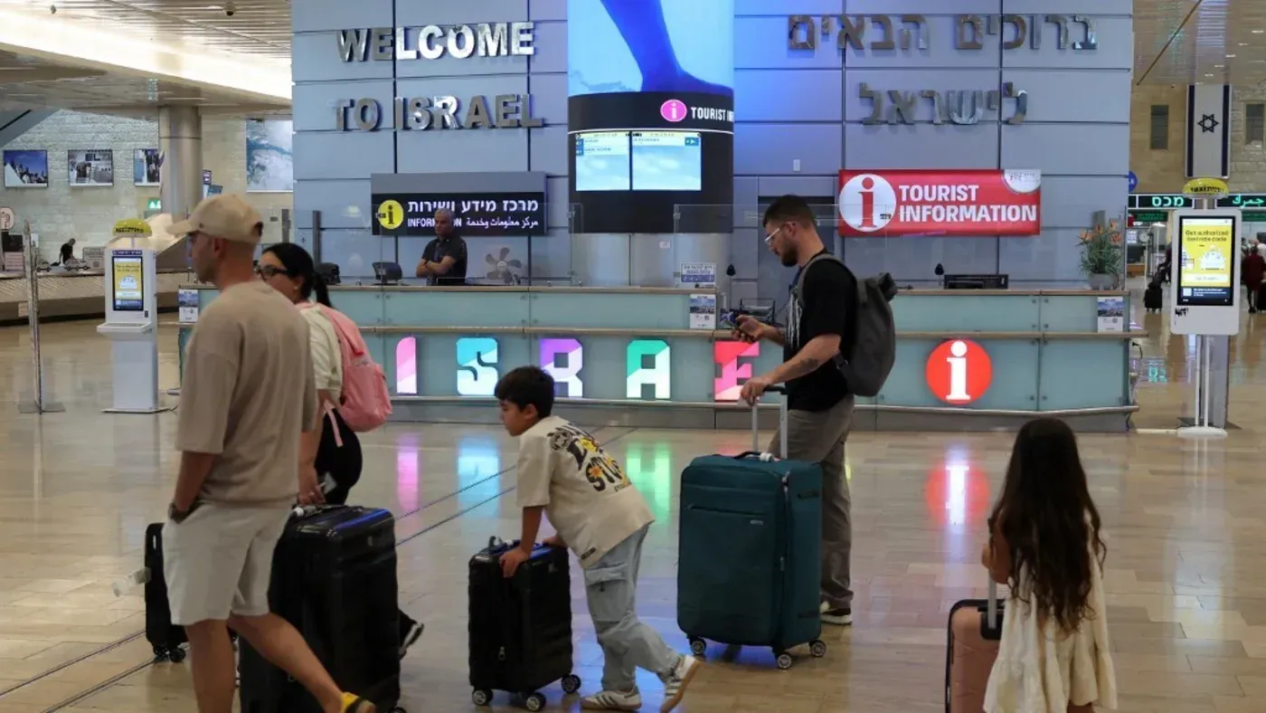 مشهد لمطار دولي في إسرائيل يظهر عائلات مسافرة مع حقائب، مع لافتة ترحيب بالزوار، في سياق زيادة مغادرة الإسرائيليين للبلاد.