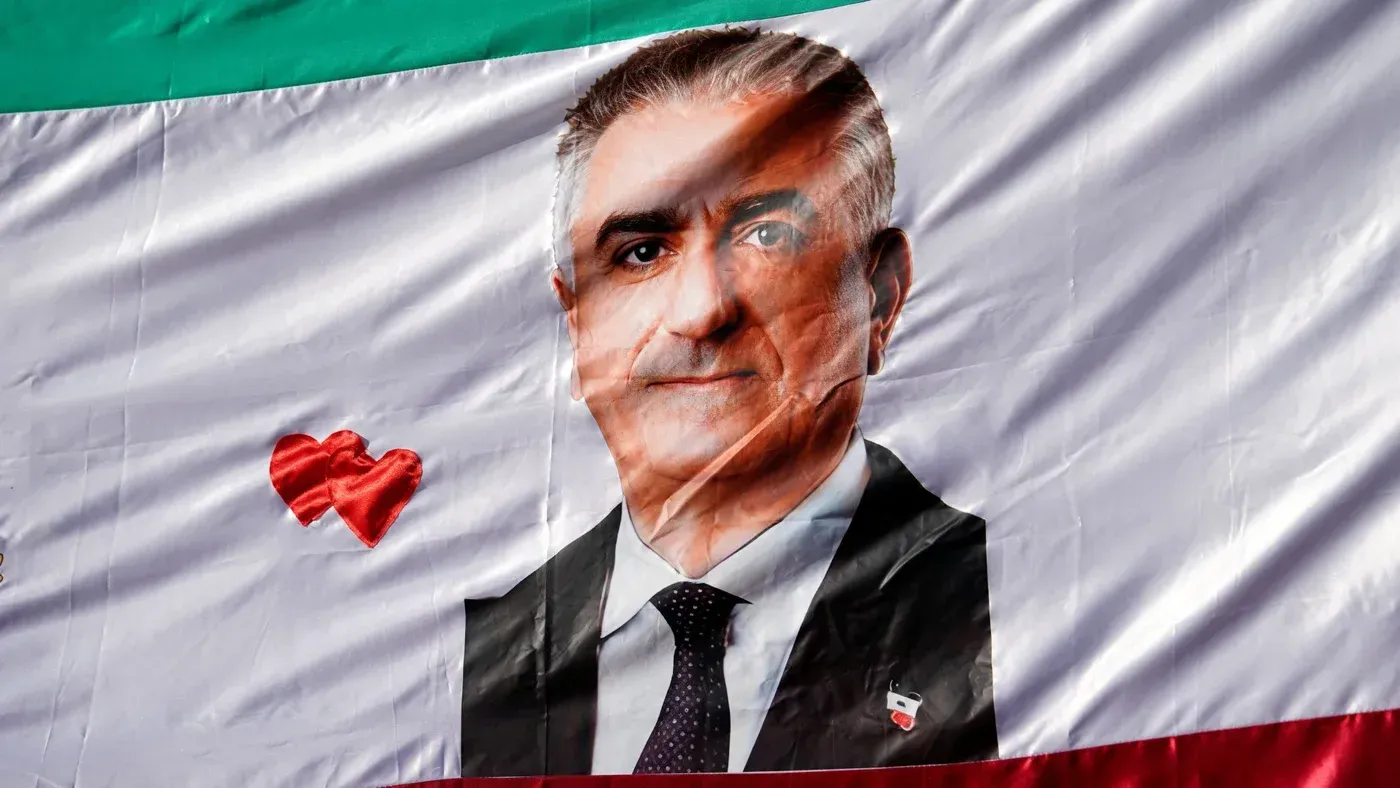 صورة لراية تحمل صورة رضا بهلوي، نجل آخر شاه لإيران، مع قلب أحمر، تعكس دعوته لتفكيك الحكومة الإيرانية وسط تصاعد التوترات.