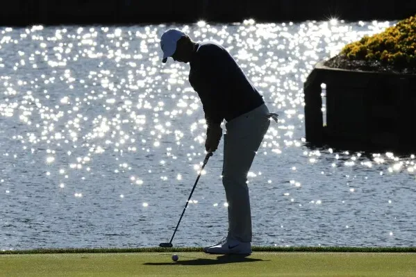 ماكلروي يستعد لضرب الكرة بالقرب من الماء في TPC Sawgrass خلال بطولة اللاعبين، مع انعكاسات ضوء الشمس على سطح الماء.