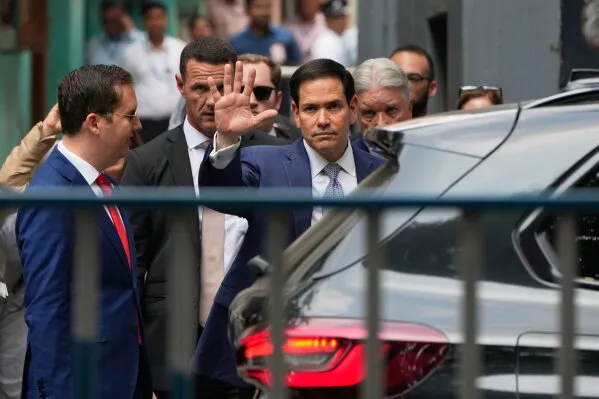 وزير الخارجية الأمريكي ماركو روبيو يلوح بيده أثناء مغادرته في سيارة، محاطًا بمساعديه، في بداية زيارته للهند.