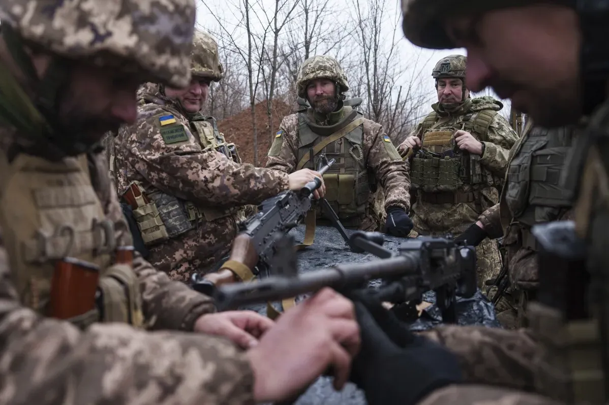 جنود أوكرانيون يرتدونuniformات عسكرية، يتجمعون حول سلاح لمناقشة الأوضاع في منطقة القتال المتوترة في دونيتسك خلال الحرب.