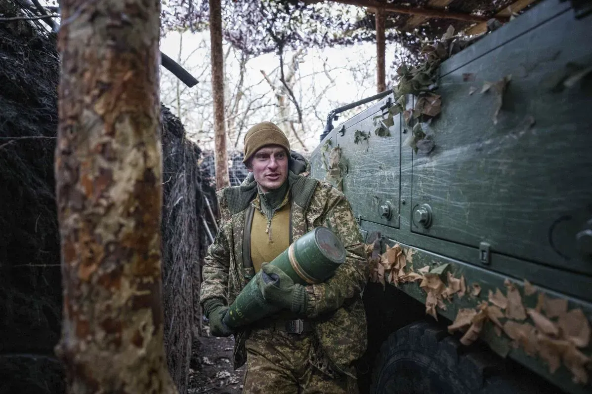جندي أوكراني يحمل قذيفة في موقع دفاعي محصن، illustrating the ongoing conflict in eastern Ukraine amidst strategic military operations.
