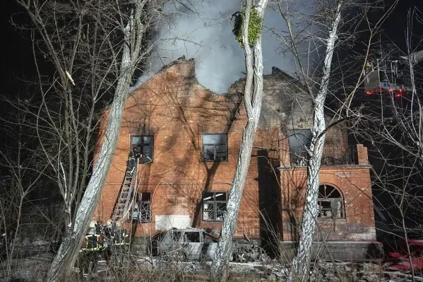 مبنى مدمر بفعل الهجوم الروسي، مع تصاعد الدخان من السقف، وعمال إطفاء يحاولون السيطرة على الحريق في موقع الهجوم.