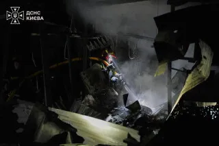 رجل إطفاء أوكراني يعمل على إخماد حريق في مبنى متضرر جراء الهجوم الجوي الروسي على كييف، مع تصاعد الدخان والدمار.