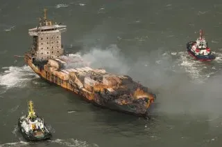 سفينة الشحن "سولونغ" تتصاعد منها أعمدة الدخان بعد اصطدامها بناقلة نفط، مع وجود قوارب إنقاذ بالقرب من موقع الحادث.