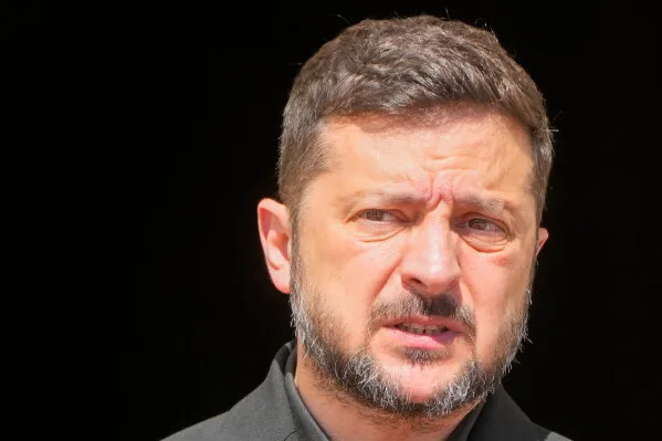 الرئيس الأوكراني فولوديمير زيلينسكي يتحدث بجدية مع خلفية مظلمة، في سياق تحذيرات من هجوم روسي وعمليات الطائرات المسيّرة.