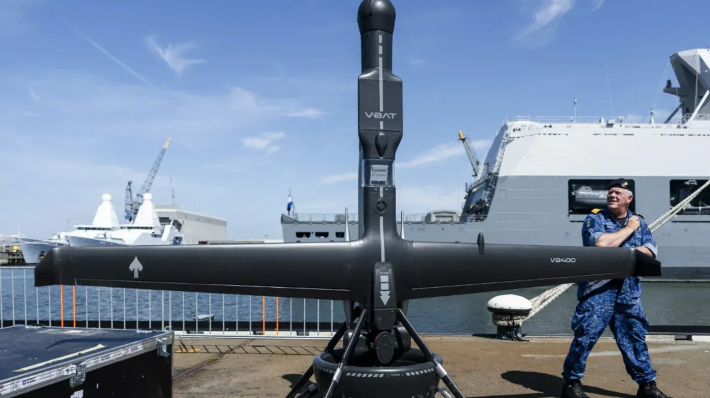 طائرة V-Bat بدون طيار من شركة Shield AI، تُظهر استخدام الذكاء الاصطناعي في العمليات العسكرية، مع وجود بحار وسفن في الخلفية.