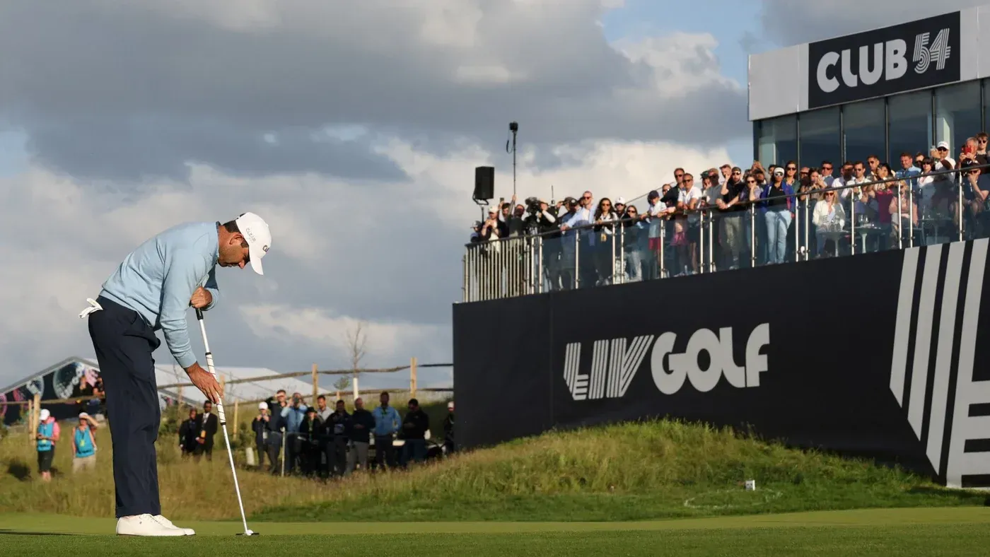 لاعب غولف يقوم بتسديد الكرة في بطولة LIV Golf، مع حشد من المشجعين في الخلفية، يظهر شعار البطولة.