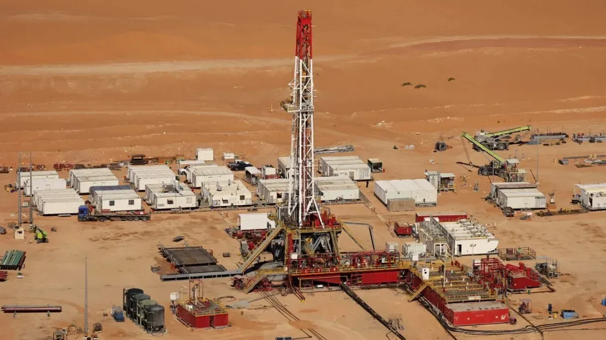 منصة حفر نفطية في الصحراء السعودية، محاطة بمرافق دعم، تعكس جهود المملكة لزيادة صادرات النفط وسط تحديات السوق.