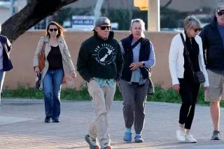 مجموعة من الأشخاص يسيرون في منطقة عامة، مع التركيز على شخص يرتدي سترة داكنة ونظارات شمسية، في سياق بحث عن نانسي غوثري.