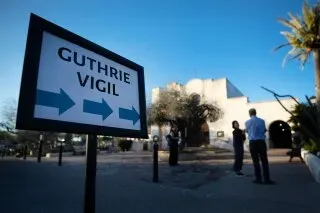 لافتة تشير إلى وقفة احتجاجية لدعم نانسي غوثري، مع وجود أشخاص في الخلفية، في موقع الحدث بتوكسون، أريزونا.