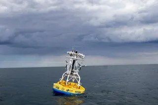 عوّامة بحثية صفراء تطفو على سطح المحيط تحت سماء غائمة، تمثل جزءًا من شبكة Ocean Observatories Initiative لرصد المحيطات.
