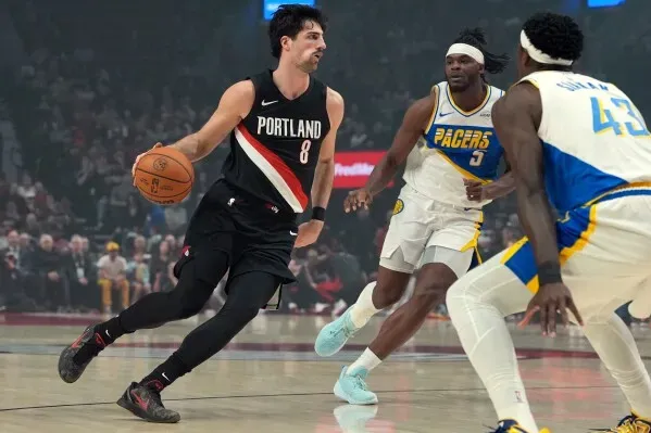 دينى أفديجا، لاعب بورتلاند تريل بليزرز، يتجاوز مدافعين من إنديانا بيسرز أثناء المباراة، مع التركيز على مهاراته في المراوغة.