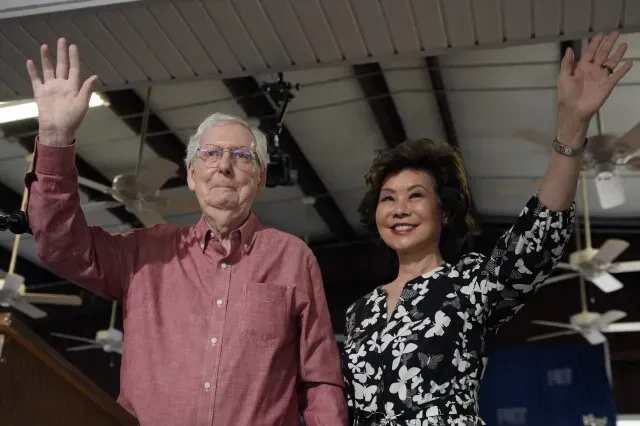 م Mitch McConnell وإلين تشاو يلوحان للجمهور خلال حفل توسيع أرشيفهما في جامعة لويزفيل، معبرين عن شكرهما ودعمهما المتبادل.