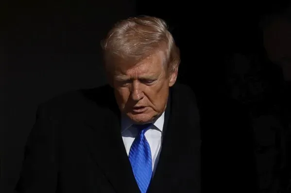 صورة لرجل يرتدي بدلة داكنة مع ربطة عنق زرقاء، يبدو عابسًا وهو يغادر مكانًا مظلمًا، مما يعكس أجواء التوتر السياسي المتعلقة بأمن المطارات.