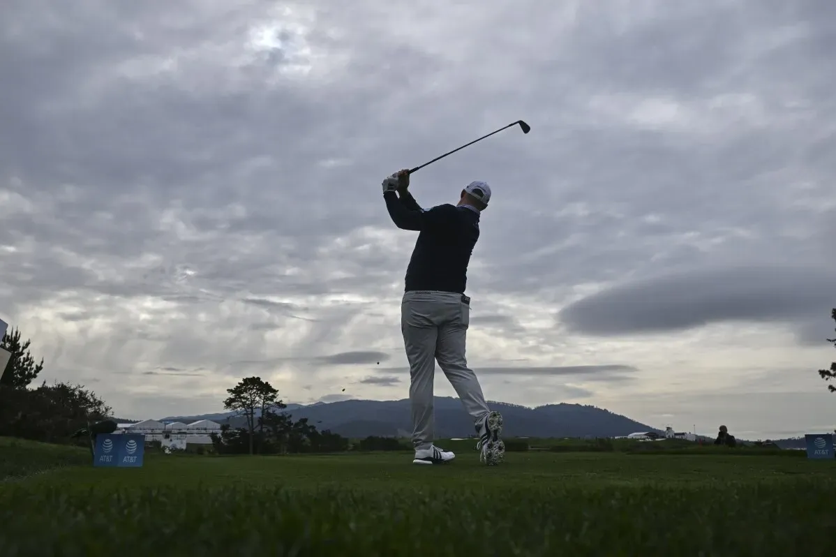 سيب ستراكا يسدد كرة الغولف في بطولة AT&T Pebble Beach Pro-Am تحت سماء غائمة، مع جبال في الخلفية، بينما يتصدر المنافسة.