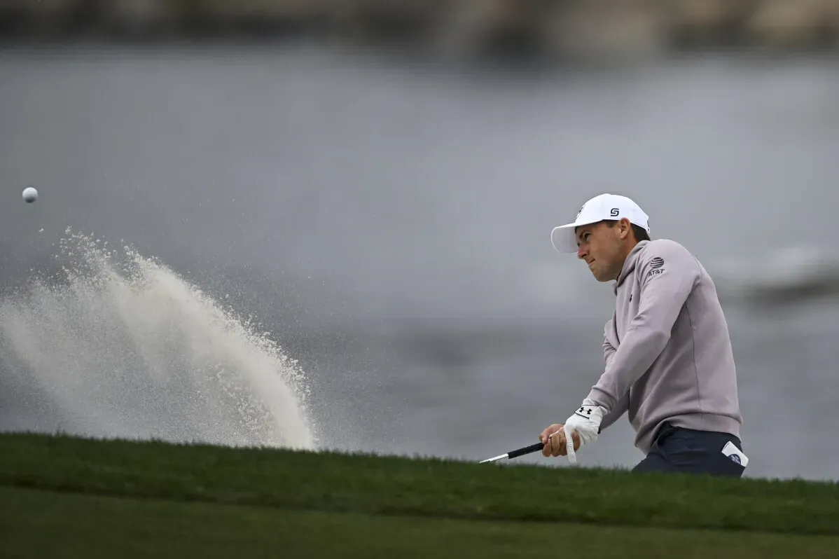 لاعب جولف يستعد لضرب الكرة من منطقة رملية خلال بطولة AT&T Pebble Beach Pro-Am، مع خلفية من البحر والسماء الغائمة.
