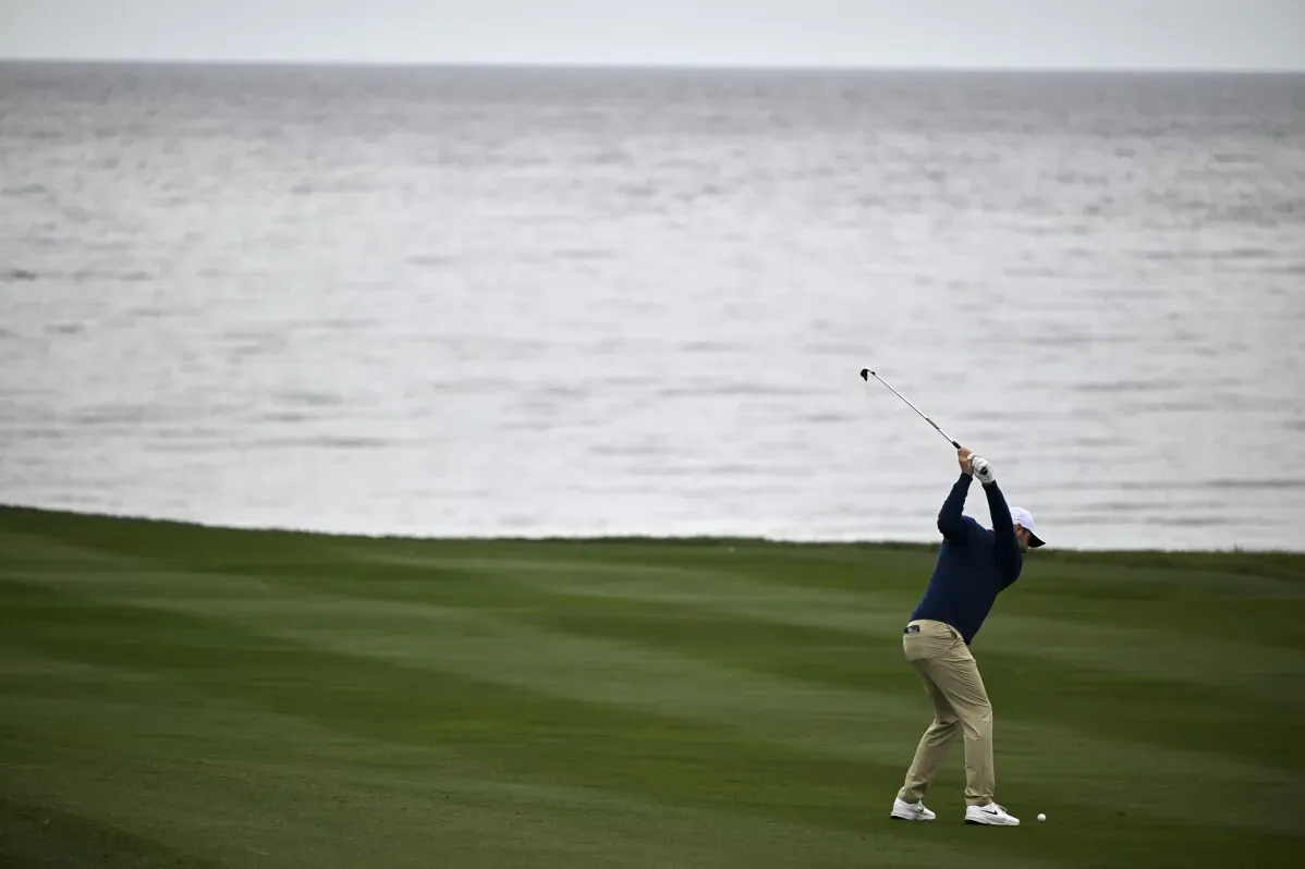 لاعب غولف يسدد الكرة نحو المحيط في بطولة AT&T Pebble Beach Pro-Am، وسط أجواء باردة وعاصفة.