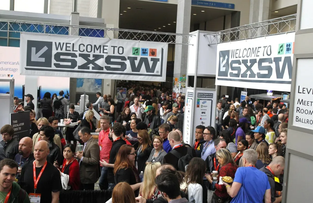 حشود من الزوار يتجمعون تحت لافتة ترحيب بمهرجان SXSW، حيث يظهر حماس كبير للأفلام والفعاليات الثقافية.