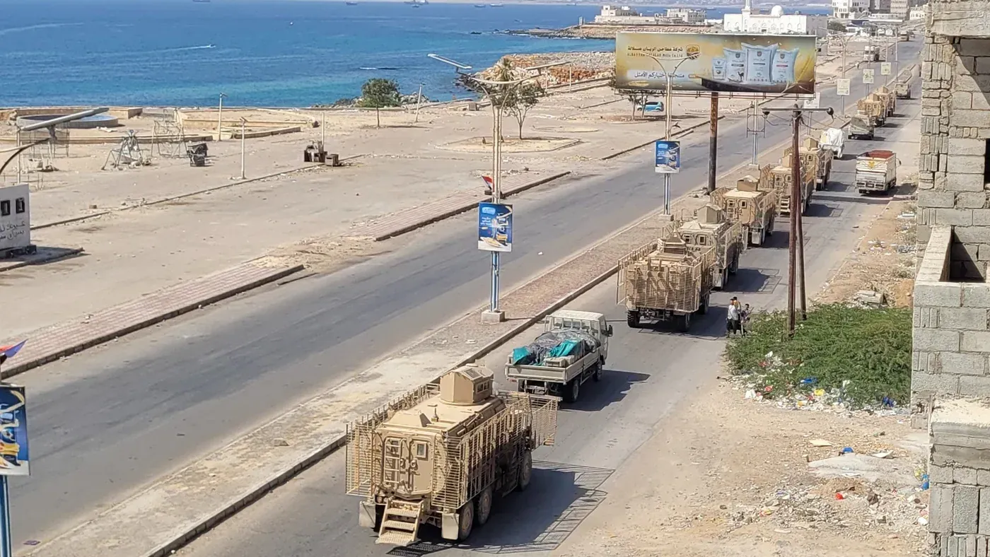 قافلة عسكرية تتقدم على طريق ساحلي في جنوب اليمن، مع وجود البحر في الخلفية، تعكس التوترات المتزايدة بين القوات المدعومة من السعودية والمجلس الانتقالي الجنوبي.