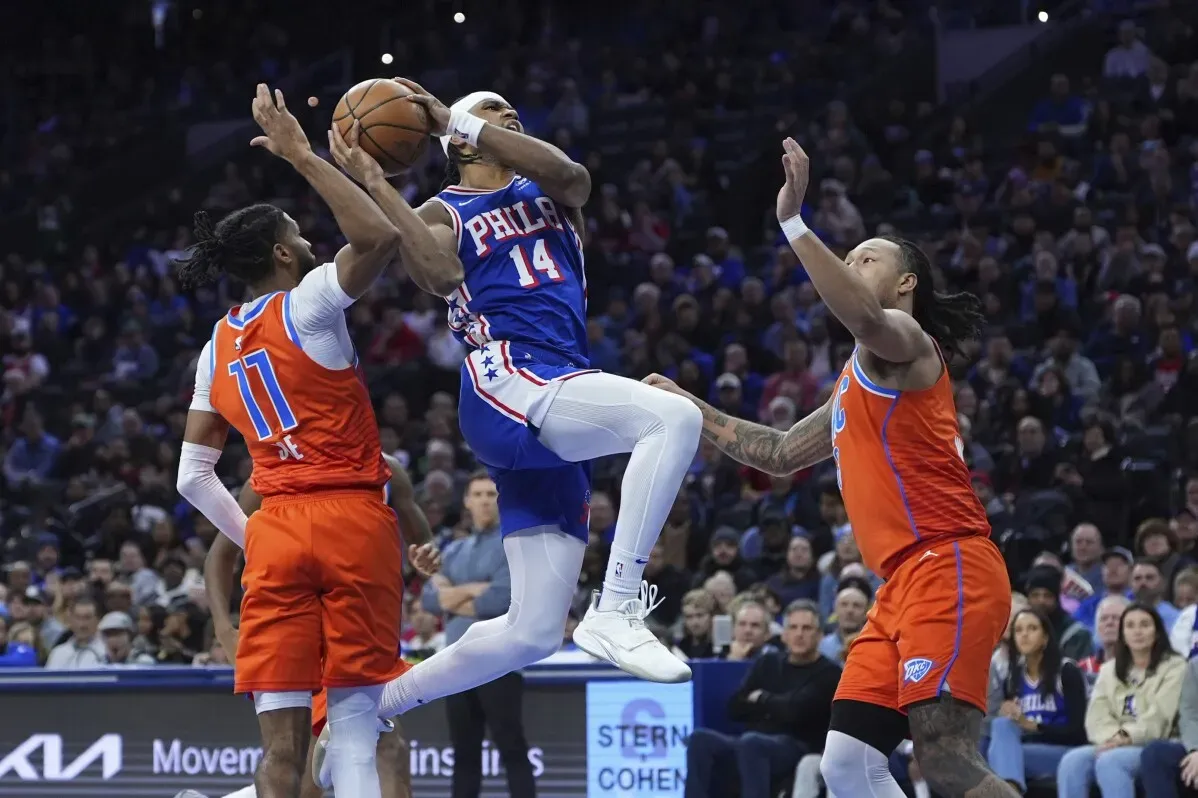 لاعب من فريق فيلادلفيا 76ers يسجل نقطة وسط ضغط من لاعبين من أوكلاهوما سيتي ثاندر، في مباراة مثيرة في دوري NBA.