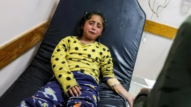 طفلة فلسطينية تبكي أثناء تلقيها العلاج في مستشفى، تعكس معاناتها إثر العدوان الإسرائيلي على غزة.