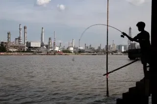 شاب يصطاد في نهر بالقرب من مصنع لإنتاج وقود الطائرات المستدام في سنغافورة، حيث تزداد جهود استخدام الوقود الأنظف.