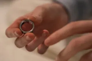 خاتم Oura Ring في يد شخص، يُستخدم لتتبع النوم والصحة، ويعكس أهمية التكنولوجيا في تحسين جودة النوم.