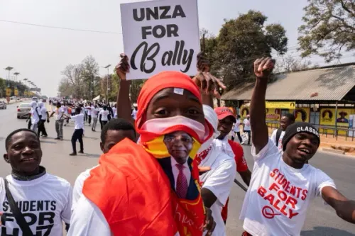 أنصار الرئيس الزامبي Hakainde Hichilema يحتفلون في شارع عام خلال الحملة الانتخابية، مع لافتات داعمة وشعارات انتخابية.