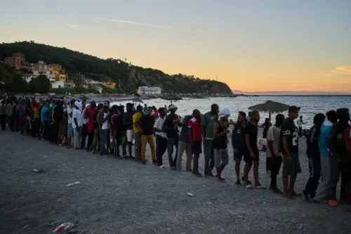 صف طويل من المهاجرين ينتظرون على شاطئ في سبتة، في ظل أزمة الهجرة غير النظامية بين المغرب وإسبانيا.