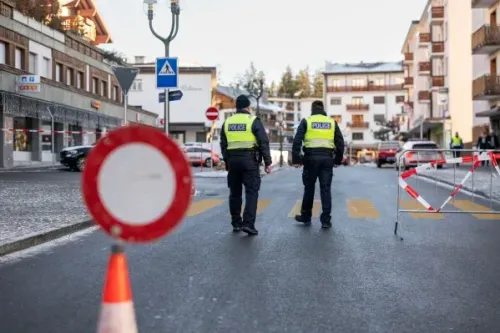 رجال شرطة يرتدون سترات عاكسة يتفقدون موقع الحادث في منتجع كرانس مونتانا السويسري بعد حريق مميت في حانة.