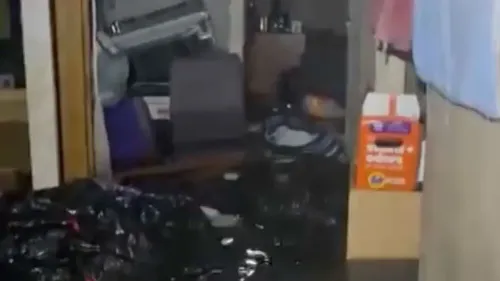 غمر الماء غرفة منزل ستيفن أنافر بعد إعصار هالونج، مع وجود أكياس بلاستيكية وصناديق تطفو حول الأثاث المغمور.